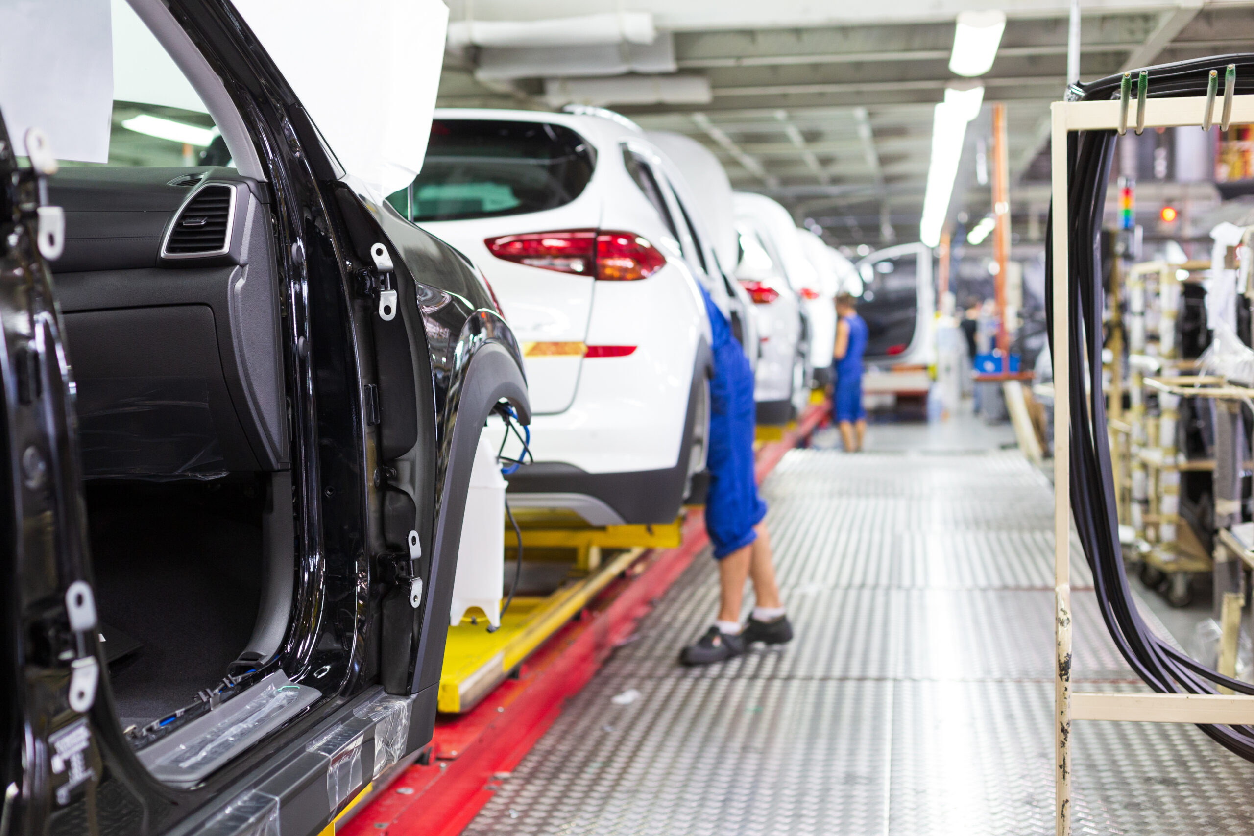 image of automotive manufacturing employee inspecting cars